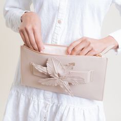 The STROLL is a slim leather clutch accented with a flower and makes accessorizing a natural art form. A hand loop makes this clutch easy to carry and ultra chic. Color: Nude 12"W x 8"H. (Interior capacity: small.) Leather Lined zip closure Clutch Imported Spring Evening Clutch With Detachable Handle, Spring Clutch With Detachable Handle, Chic Blush Clutch For Evening, Chic Beige Clutch With Zipper Pouch, Chic Clutch For Spring Season Gift, Chic Spring Clutch For Gift, Chic Spring Clutch As Gift, Spring Beige Clutch For Formal Occasions, Chic Beige Clutch For Spring