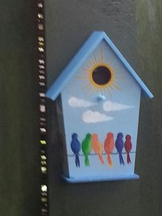 a birdhouse with birds painted on it and the sun in the sky above them