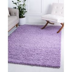 a living room with a white chair and purple rugs on the floor in front of a couch