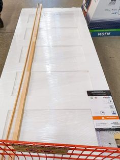 a pile of white cardboard sitting on top of a store floor next to a red shopping cart