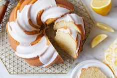 a lemon bunt cake with white icing on a cooling rack next to sliced lemons