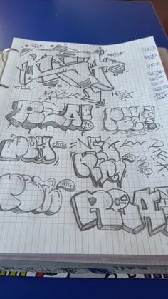 a notebook with graffiti written on it and lined in papers next to a pencil drawing