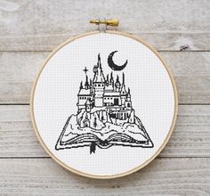 a cross stitch book with a castle on it in the shape of an open book