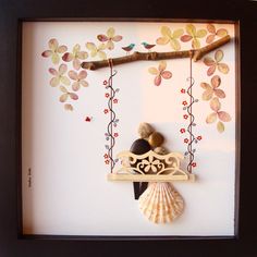 a shadow box frame with a bird on a swing and seashells hanging from the branch