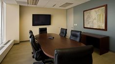 an empty conference room with black leather chairs and a flat screen tv on the wall