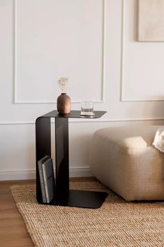 a table with a magazine rack on it in front of a couch and coffee table