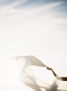 a woman holding a white scarf in her hand