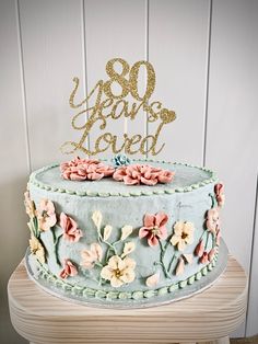 A blue cake with delicate flowers Fondant Floral Cake, Garden Party 80th Birthday, Birthday Themes For Grandma, 80th Birthday Cake For Women Elegant, 80th Birthday Party Ideas For Grandma Cake, 80th Birthday Cake Ideas For Grandma, 80th Bday Cake, 80 Th Birthday Cake