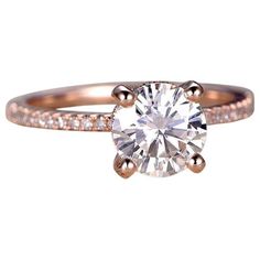 a rose gold engagement ring with diamonds on the band and a round cut diamond in the center