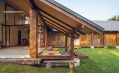 a wooden structure sitting in the middle of a grass covered field next to a building