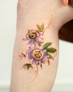 a close up of a person's leg with tattoos on it and flowers in the middle