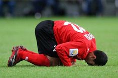 a soccer player laying on the ground with his head in his hands while looking down