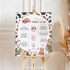 a baby's first year sign is shown on an easel next to flowers