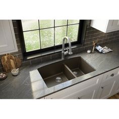 a kitchen sink sitting under a window next to a counter