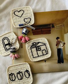 four crocheted coasters with black writing on them and a person standing in the background