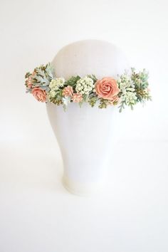 a white mannequin headpiece with flowers and greenery on it's sides