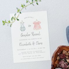 a baby announcement card next to a wooden bowl filled with rocks