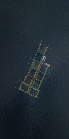 an aerial view of two people on a raft in the middle of water with nets attached to it