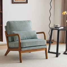 a living room with a chair, table and vase on the floor next to it