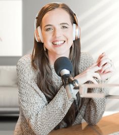 a woman wearing headphones sitting at a table with a microphone in front of her