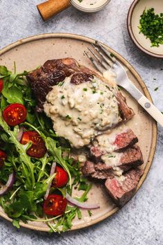 a plate with steak, salad and dressing on it