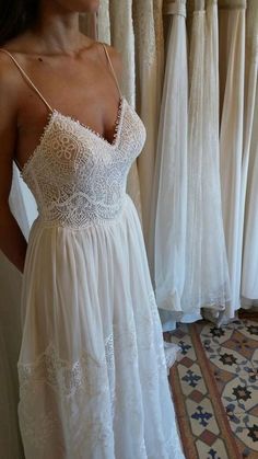 a woman in a white dress standing next to some curtains and looking into the mirror