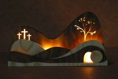 a lighted sculpture with a cross and tree on it