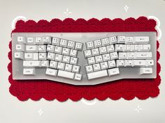 a computer keyboard with white keys sitting on top of a red placemat in front of a white background