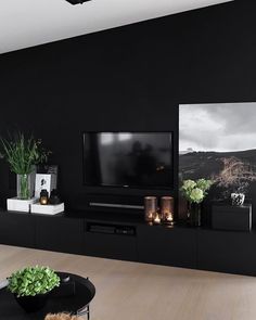 a living room with black walls and wooden flooring, two pictures on the wall