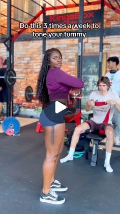 a woman standing on top of a bench in a gym