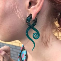 a close up of a person wearing earrings with swirl designs on them and one ear