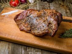 a steak on a cutting board with garlic and tomatoes