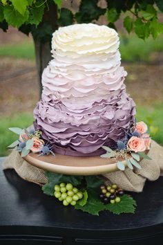 a multi - tiered cake with flowers and greenery sits on top of a table