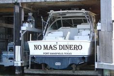 a boat is docked in the water under a bridge that reads no mas dinero