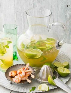 a pitcher of lemonade, limeade and shrimp on a plate with spoons