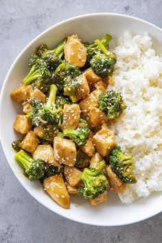 a white bowl filled with chicken and broccoli next to rice on a table