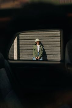 a man standing in front of a garage door with his reflection in the side view mirror