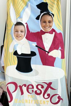 a young boy is holding up a banner with an image of two children dressed as magicians