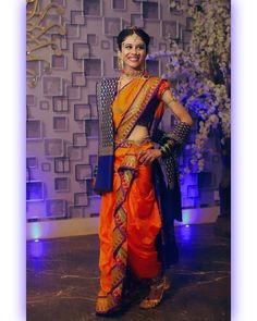 a woman in an orange sari posing for the camera with her hands on her hips