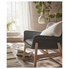 a living room with a chair, rug and potted plant on the floor in front of a window