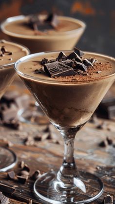 three glasses filled with chocolate pudding on top of a wooden table