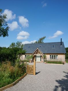 a wooden house with a black roof surrounded by greenery