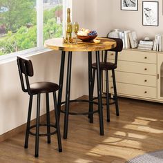 a small table with two stools next to it in front of a large window