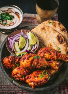 some food is on a plate and next to a bowl of sauce, pita bread, and sliced onions