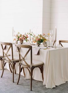 the table is set with white linens and flowers