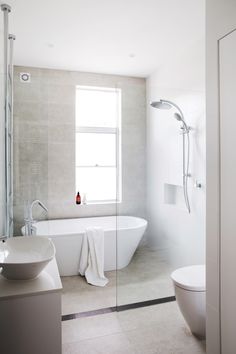 a bathroom with a bathtub, sink and toilet next to a large window on the wall