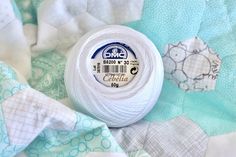 a ball of white yarn sitting on top of a blue and white quilting material