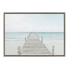 a framed photograph of a pier on the beach