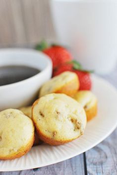 some muffins and strawberries on a plate with a cup of coffee in the background