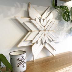 a wooden snowflake sitting on top of a table next to a potted plant